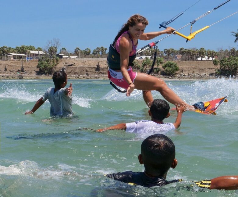 Kitesurf rider in indonesia with local kids playing in the lagoon