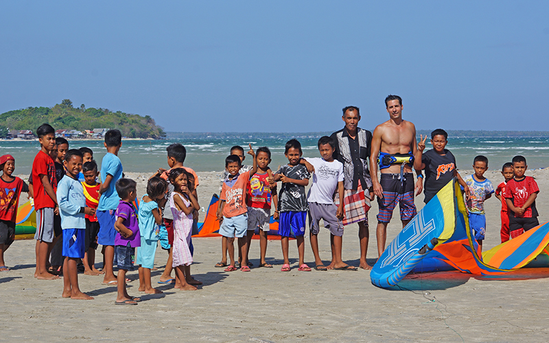 Kitesurf travelers in Indonesia surrounded by local community