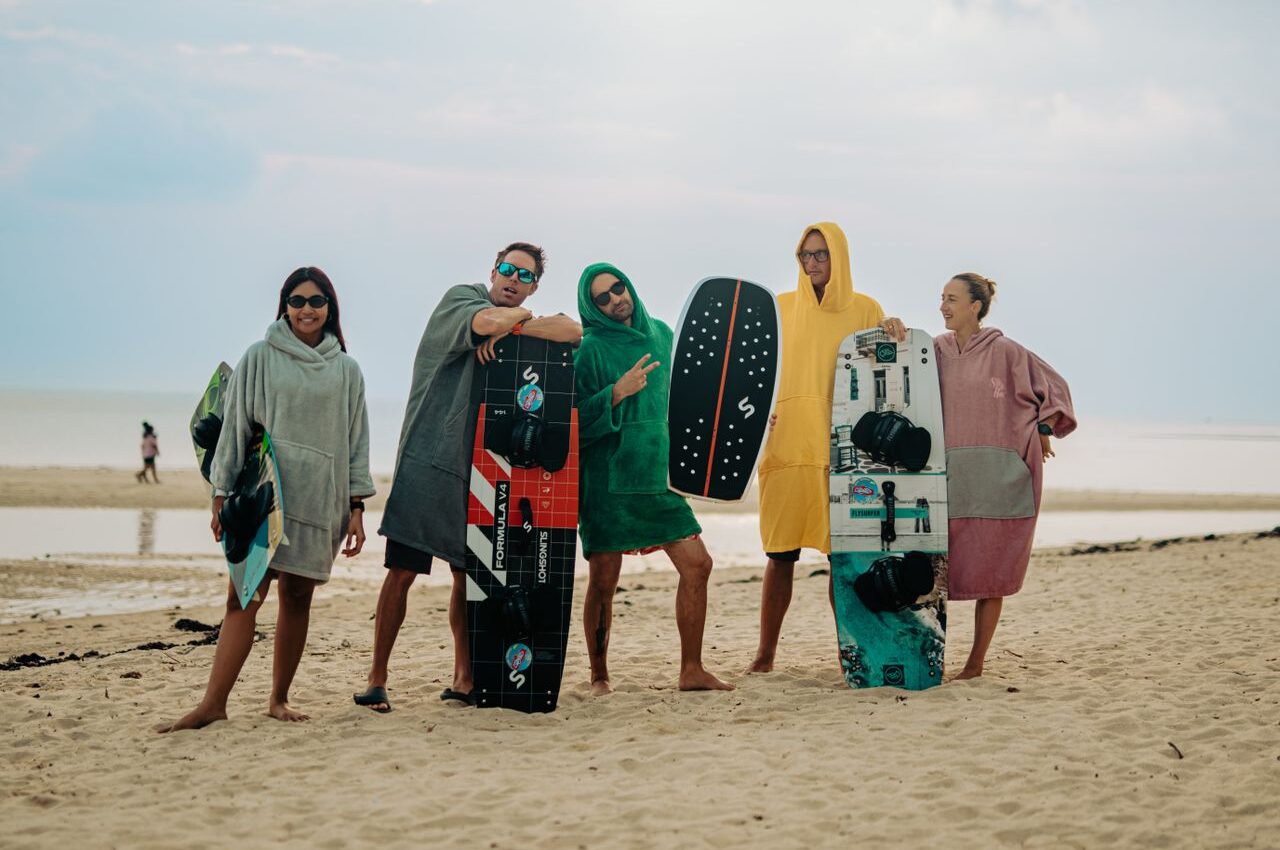 Group of kitesurfers sharing the stoke on the beach after a session