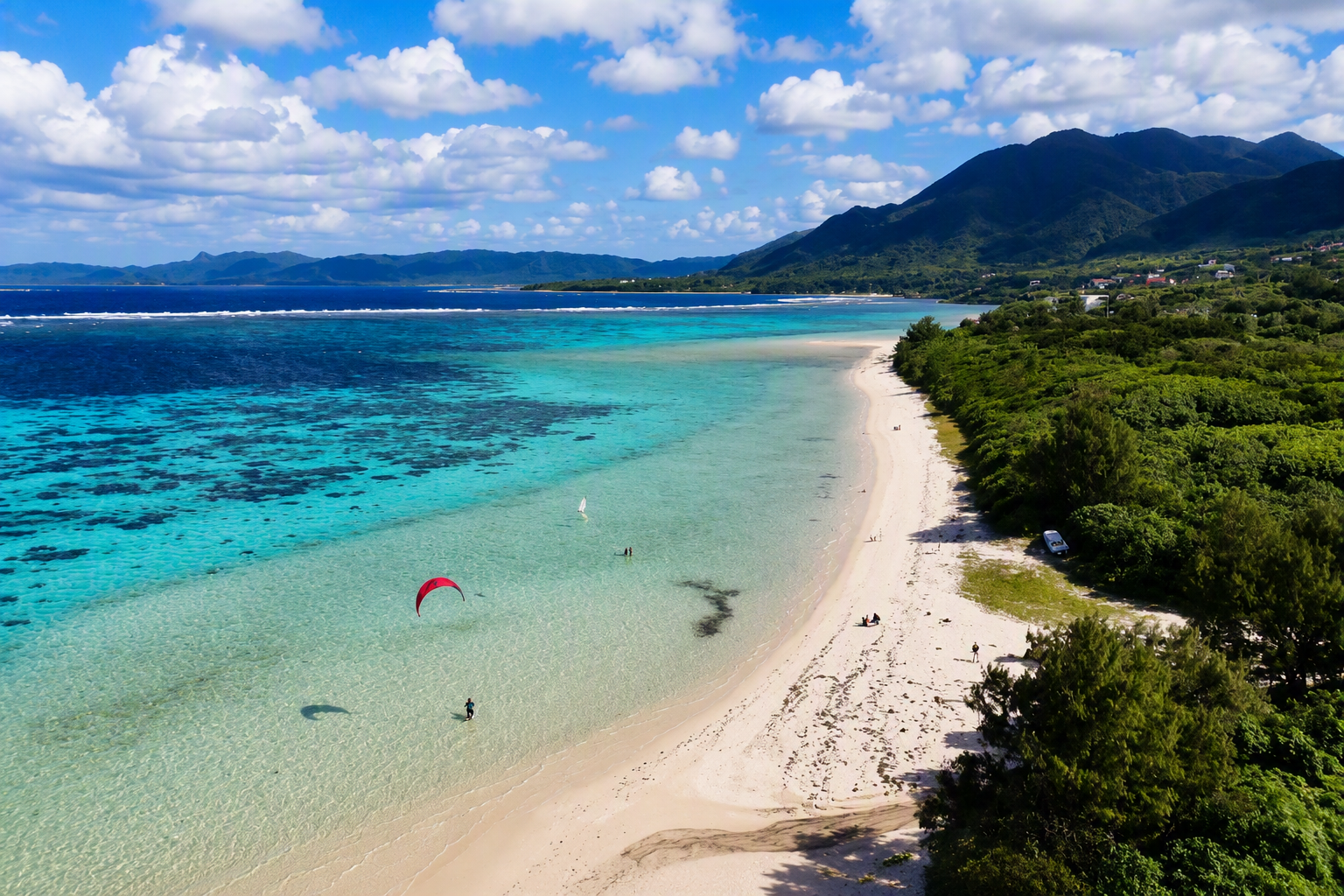 Kitesurfer riding in a shallow turquoise lagoon in Ishigaki, Okinawa, Japan.