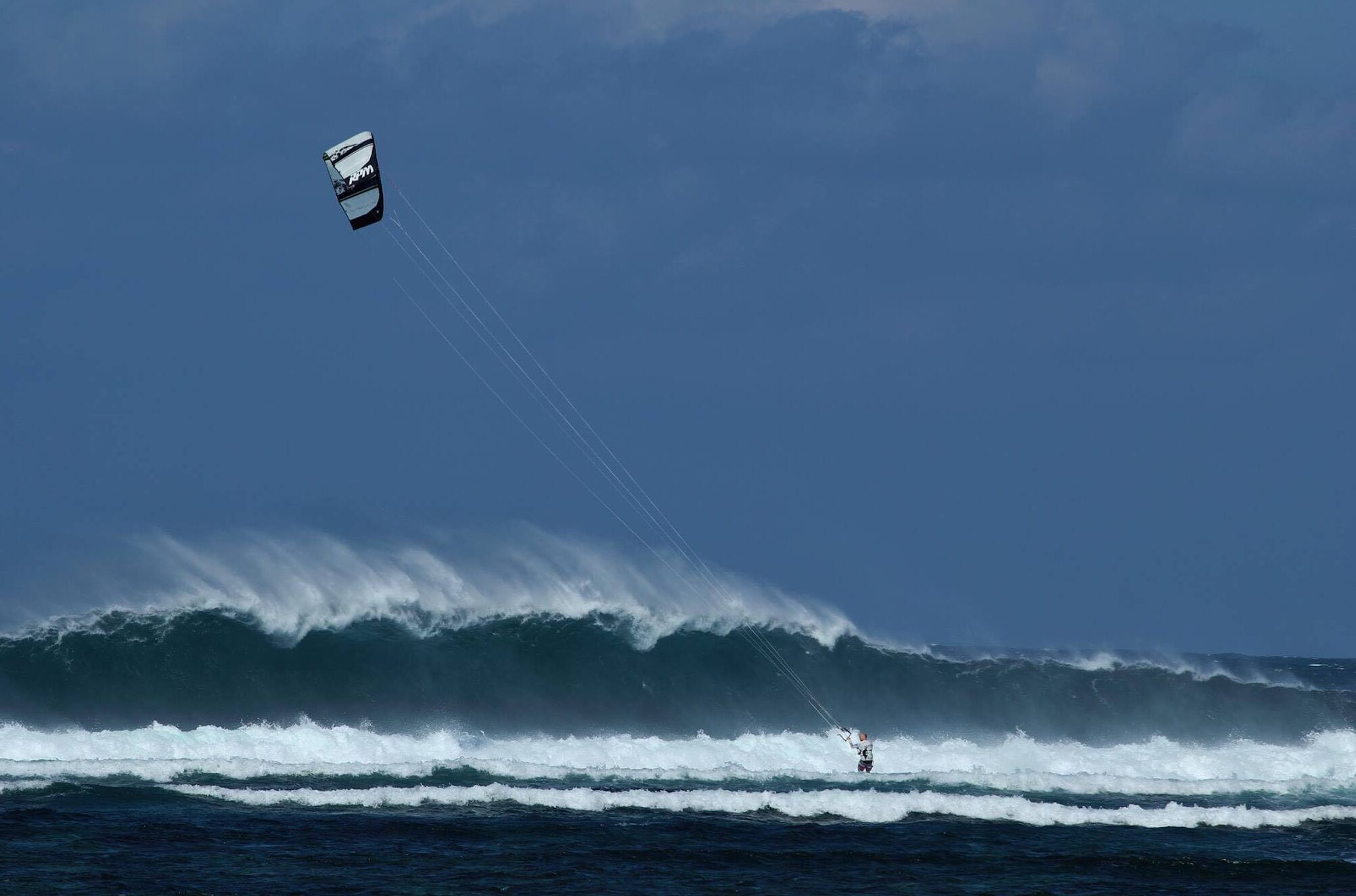 Kitesurfer riding in front of a breaking wave in Pagudpud, Philippines.